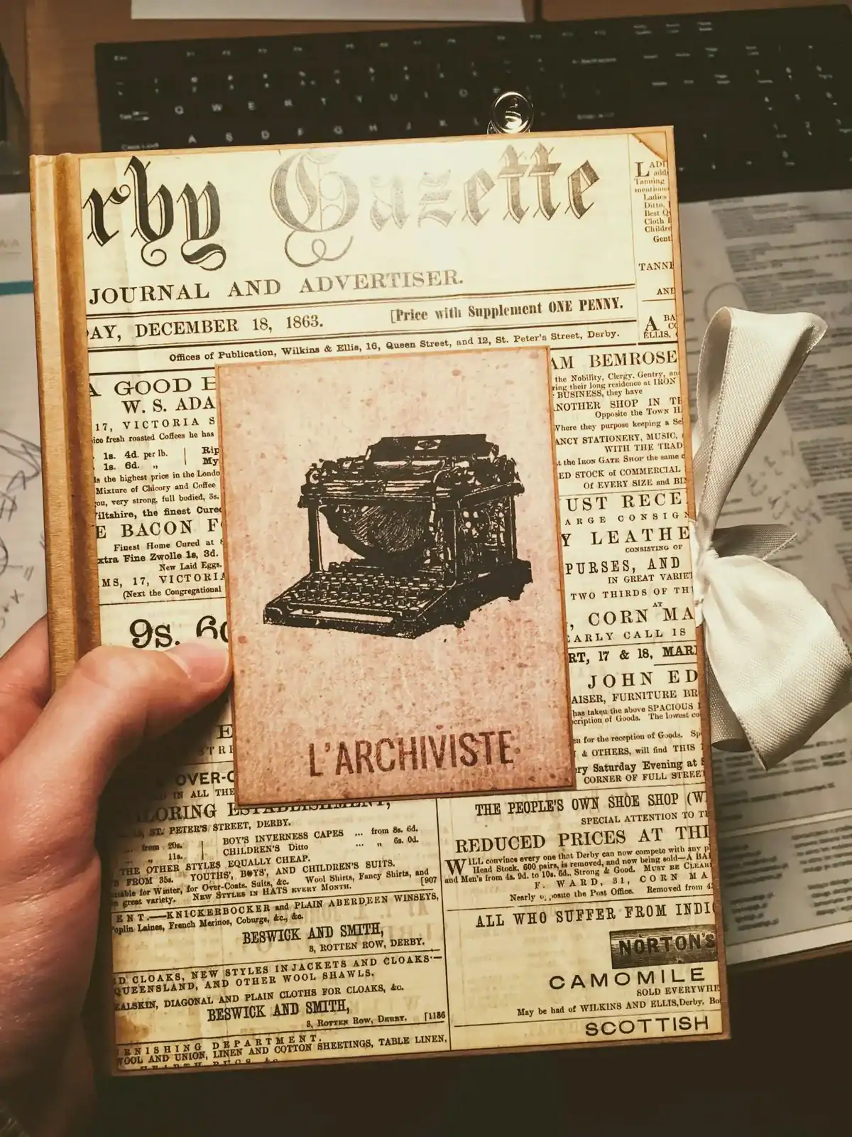 An archival notebook held above a page of old newspaper text