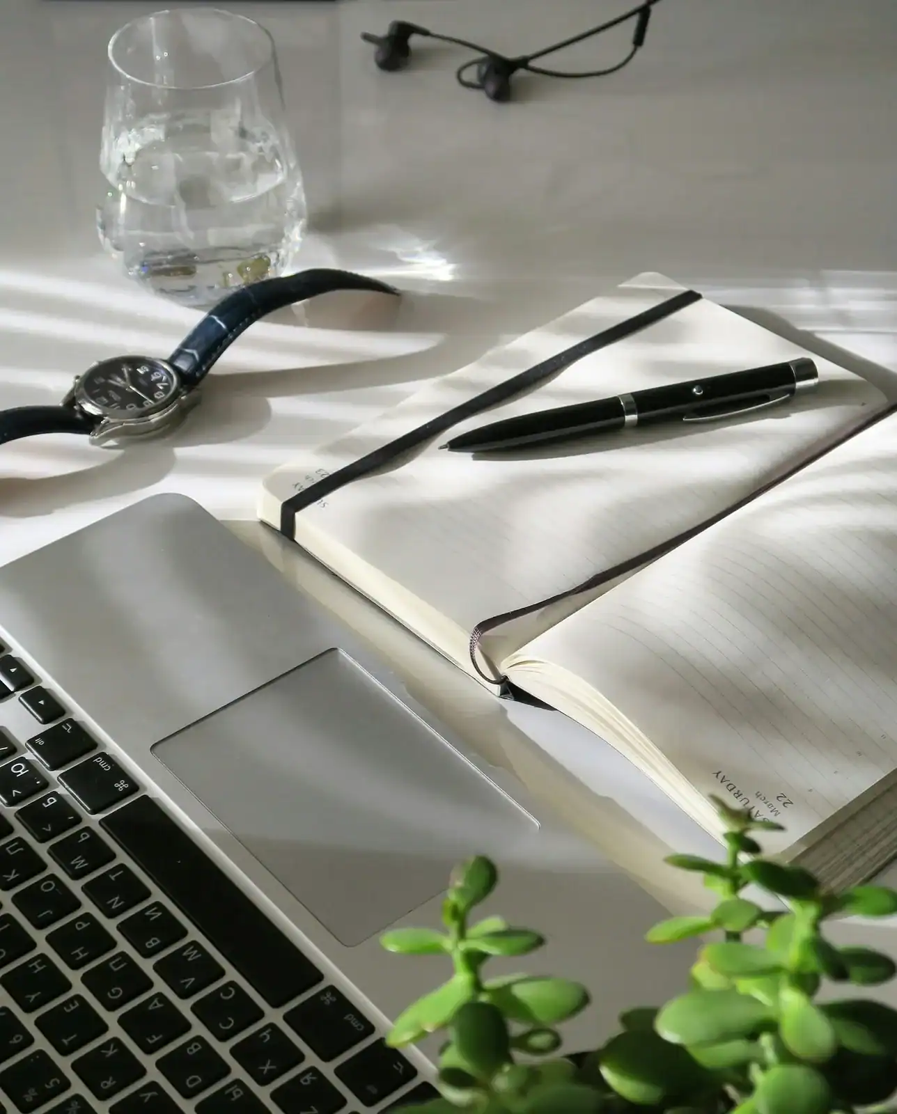 An open notebook and pen beside a laptop