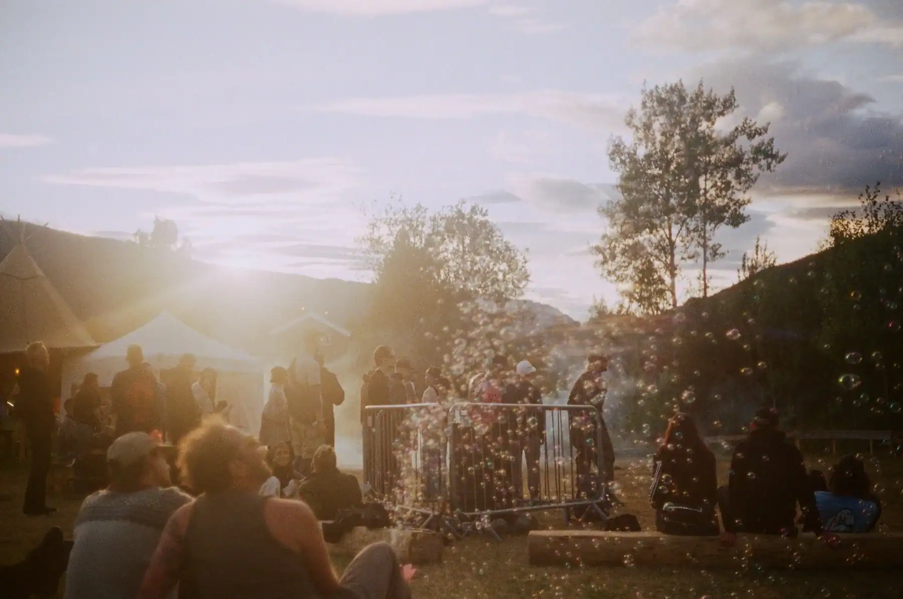 People at an outdoor gathering with bubbles floating in golden light