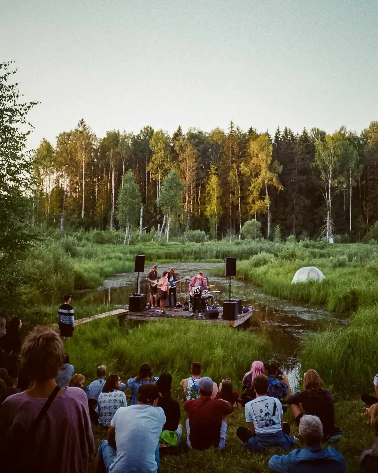 People gathered for an outdoor performance in a woodland clearing