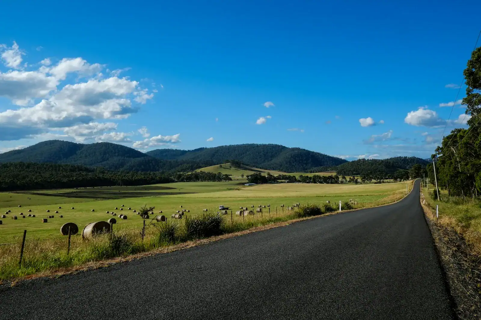 A country road beside open paddocks and distant hills