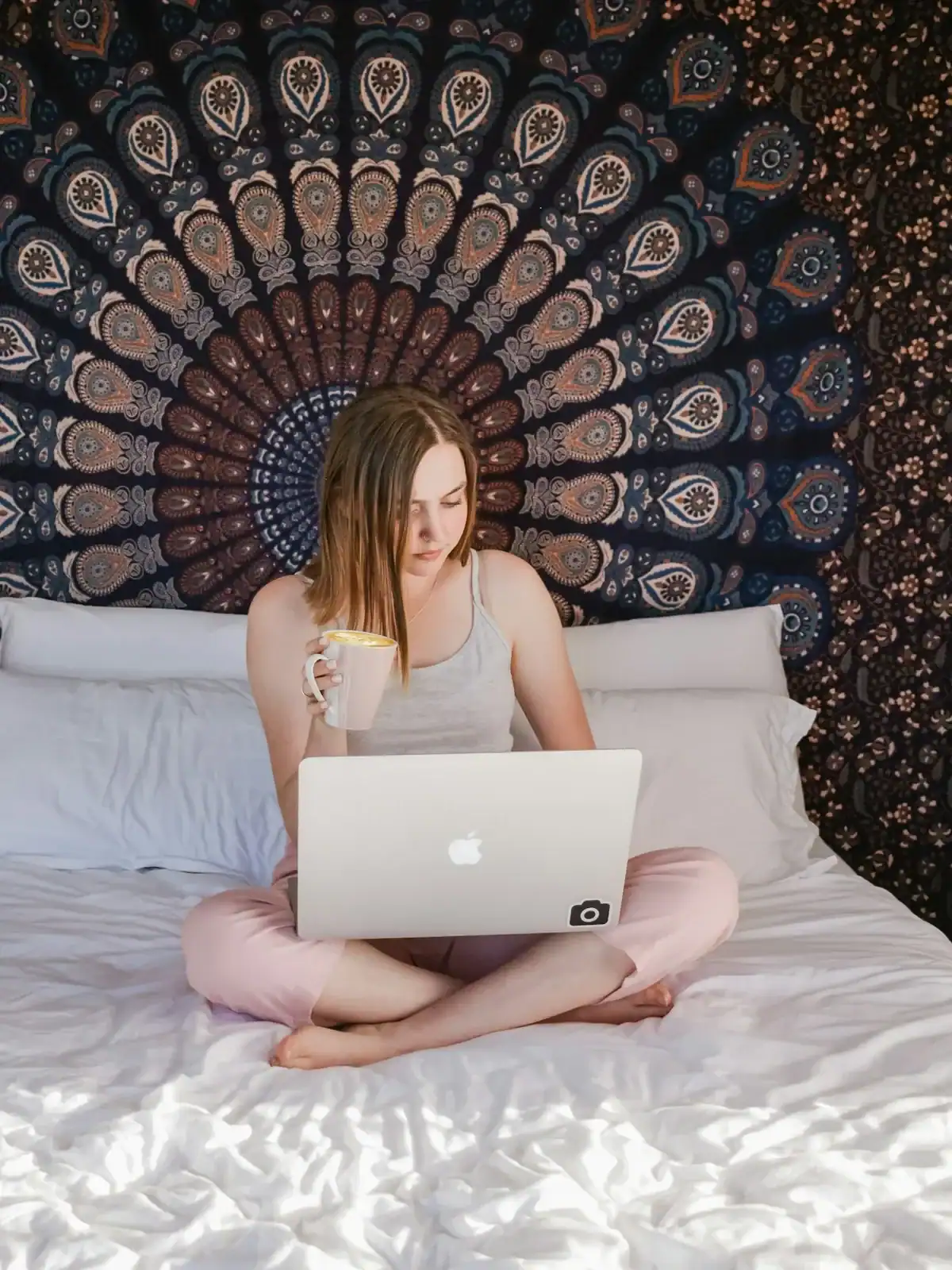 A woman taking part online with a laptop and a mug