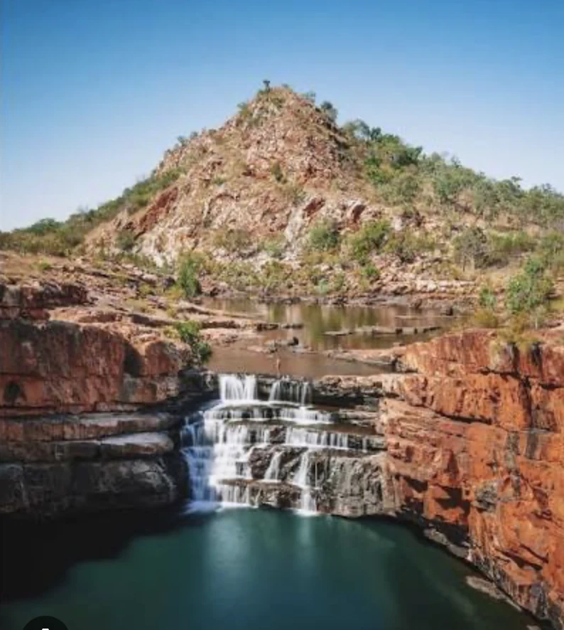 A tranquil pool and waterfall in a rugged northern landscape